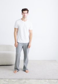 T-shirt en coton blanc et pantalon de détente gris en tissu doux. Les pantalons sont amples et présentent un design simple.
