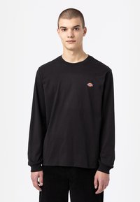 Zwart katoenen T-shirt met lange mouwen, een ronde halslijn en een klein kleurlogo op de borst. Losse pasvorm met ribgebreide manchetten en zoom.