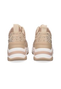 Zapatillas deportivas beige con parte superior de malla con brillos, suela blanca acolchada y parte trasera texturizada con tirador.