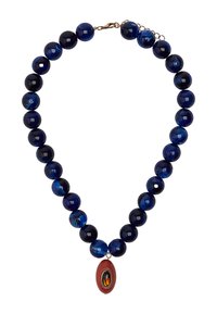 Naszyjnik z ciemnoniebieskimi okrągłymi koralikami, przeplatany jaśniejszymi marmurkowymi koralikami, oraz czerwoną owalną zawieszką w złotej oprawie.