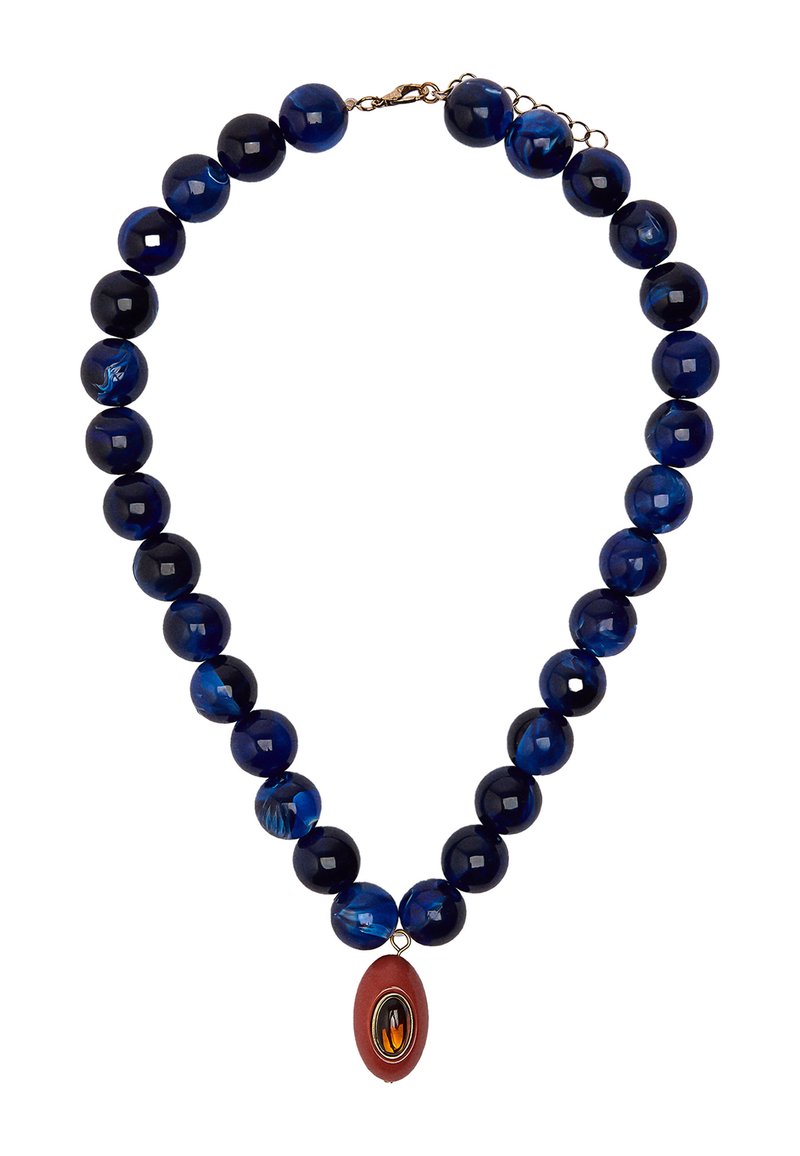Naszyjnik z ciemnoniebieskimi okrągłymi koralikami, przeplatany jaśniejszymi marmurkowymi koralikami, oraz czerwoną owalną zawieszką w złotej oprawie.