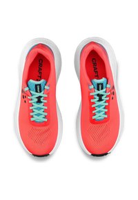 Des chaussures de course Craft avec une tige en maille corail vif, des lacets bleu clair et une semelle blanche avec des détails texturés et des accents noirs.