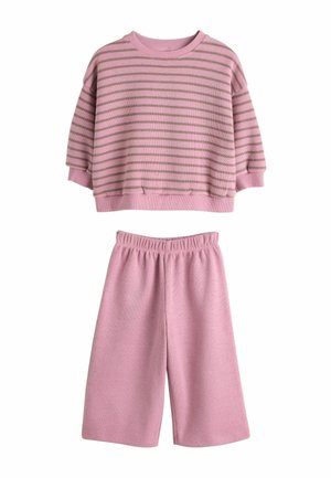 Rosa kurz geschnittener Pullover mit horizontalen hellbraunen Streifen, kombiniert mit passenden rosa Shorts mit elastischem Bund. Weiche Materialstruktur.