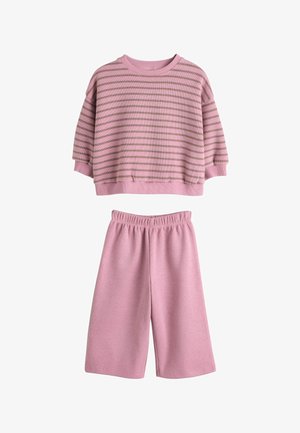 Ružový krátky sveter s horizontálnymi svetlohnedými pruhmi, v kombinácii s ružovými šortkami s elastickým pásom. Jemná textúra materiálu.