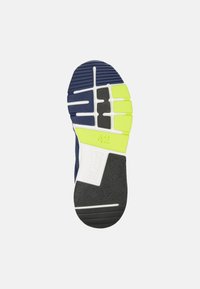 Sole di una scarpa sportiva blu con un motivo di trazione giallo e nero, con un'etichetta bianca che mostra "42" e "CAMPER."