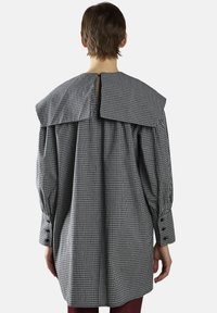 Gingham-mønstrede overdådige skjorte i sort og hvid, med en stor krave, plisseret ryg og knapmanchetter.