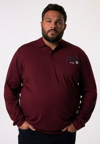 Burgunderrotes Langarm-Poloshirt mit Kragen, versehen mit dem Text und Logo "Bergabenteuer" auf der linken Brust. Weicher, glatter Stoff.