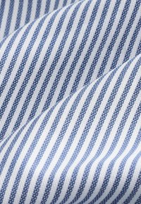 Bawełniana tkanina z niebiesko-białym wzorem w paski, z naprzemiennie cienkimi i szerokimi paskami, charakteryzująca się gładkim, fakturowanym wykończeniem.