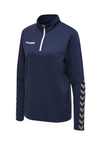 Pull-over de sport bleu marine à manches longues avec fermeture éclair blanche quart de tour, logo blanc "hummel" sur la poitrine et bandes chevrons noir-gris sur les manches.