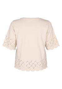 T-shirt in cotone beige con orlo scallop e dettagli a perforazione lungo il fondo e le maniche. Maniche corte e vestibilità rilassata.