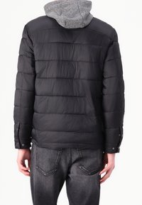 Gepolsterte schwarze Jacke mit grauer Kapuze, vertikaler Steppung, Druckknopfmanschetten und glatter Textur. Rückansicht zeigt die Form der Jacke.