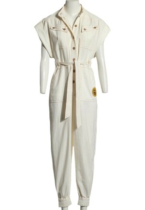 Combinaison sans manches couleur crème avec boutonnière sur le devant, ceinture à la taille, poches poitrine, poignets élastiques et patch tournesol sur la jambe droite.