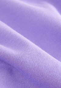 Helle lilafarbene Stoff mit glatter, weicher Textur; zeichnet sich durch ein feines Strickmuster mit subtilen Farbvariationen aus. Keine nennenswerten Verzierungen.