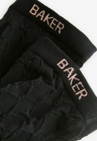 Calcetines negros con un patrón texturizado, que cuentan con un puño de punto acanalado. "BAKER" bordado en rosa en el puño. Material suave y elástico.