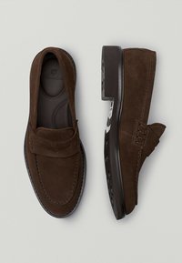 Brune ruskinds loafers med en glat overflade, der har en syet detaljer og en firkantet tå. Sålen er sort med et struktureret grebsmønster.