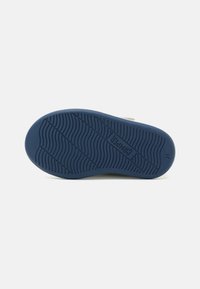 Semelle de chaussure en caoutchouc bleu avec des rainures texturées et une marque. Présente une forme ronde et un profil plat, conçu pour offrir adhérence et confort.