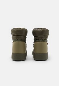 Bottines vertes avec un dessus rembourré et matelassé, une partie inférieure en plastique lisse et une semelle en caoutchouc texturé. Lacets réglables sur les côtés.