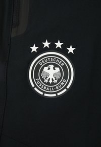 Schwarzer Sportstoff mit einem kreisförmigen weißen Logo, das einen Adler und fünf Sterne über ihm zeigt. Der Text lautet "Deutscher Fußball-Bund."