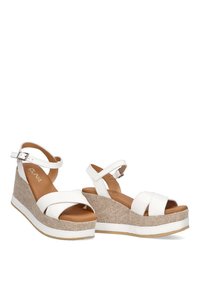 Sandalias de cuña blancas con una plataforma de color beige texturizada, que cuentan con correas anchas y una correa ajustable en el tobillo. Plantilla suave en color marrón claro para mayor comodidad.