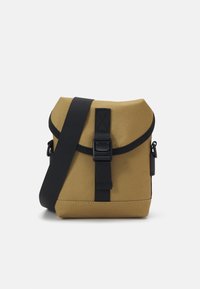 Brown fabric crossbody bag with a flap closure, black strap, and buckle detail. Compact square shape with a textured finish.