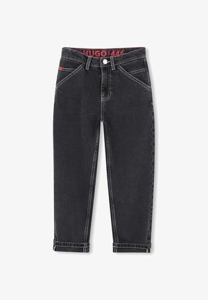 Fekete farmernadrág egyenes szabással, fehér varrással és felhajtott szegéllyel. Jellemzője a piros márkázott derékpánt és a hagyományos elülső/hátsó zsebek.