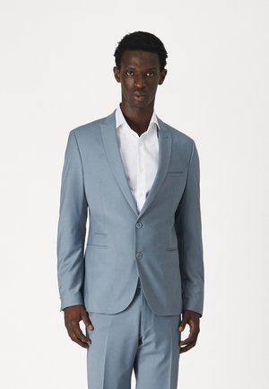 Light blue suit jacket with two buttons, notch lapels, and slim-fitting design. Worn over a white dress shirt. Tailored style with pockets.