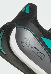 Sort sportsko med teal accenter og en tekstureret overdel. Har en grå hæl med et logo og hvid outsole detaljering.