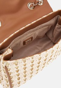 Öppen beige och guld vävd handväska med ljust brun läderkant, guldkedjestraps och beige tyginteriör med en zipficka märkt GUESS.