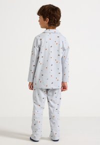 Hellblaues Pyjama-Set bestehend aus einem langärmeligen Oberteil und einer Hose, geschmückt mit kleinen, bunten Blatt- und Blumenmustern überall.