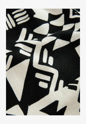 Fekete-fehér szövet, amely absztrakt geometrikus mintákat, köztük háromszögeket és vonalakat tartalmaz, texturált felülettel és puha eséssel.