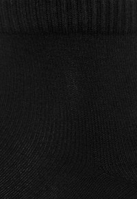 Calzino nero con texture a coste, materiale morbido e finitura liscia. Presenta una punta senza cuciture per il comfort e un'apertura elasticizzata.