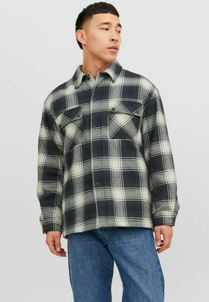 Plaid shirt in gray and black tones, made of flannel, features two chest pockets and button closure, with a relaxed fit and long sleeves.