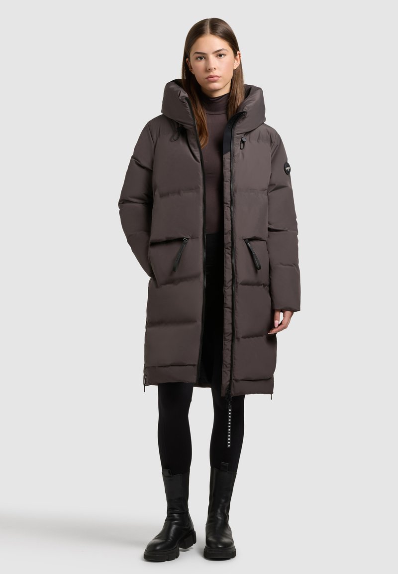 Puberová bunda v tmavošedej farbe s kapucňou, zipsovými vreckami a priliehavým strihom. Má hladkú textúru a elastické manžety.