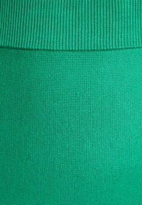 Green knitted fabric featuring a textured, stretchy design with ribbing at the top. Smooth, uniform surface with no visible patterns or accents.