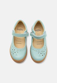 Chaussures en cuir vert menthe avec un bout arrondi, une sangle Velcro et des découpes décoratives sur le dessus. Semelles en caoutchouc brun naturel.