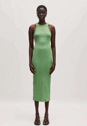 Grünes, ärmelloses Midi-Kleid aus dehnbarem Stoff mit taillierter Silhouette, rundem Ausschnitt und subtiler Textur. Kombiniert mit schwarzen Sandalen.