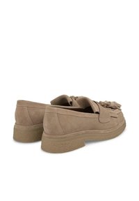 Scarpe slip-on in suede beige chiaro con punta arrotondata, superficie texturizzata e dettaglio a nappa nella parte anteriore. Presentano una suola in gomma spessa e testurizzata.