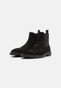 Botine Chelsea din suede negru, cu un finisaj texturat, vârf rotund, panouri elastice pe laterale și o talpă din cauciuc căptușită.