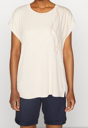 Chemise beige à manches courtes avec un col rond. Présente des accents décoratifs ondulés et rayés dans une teinte plus claire. Tissu doux avec une coupe décontractée.