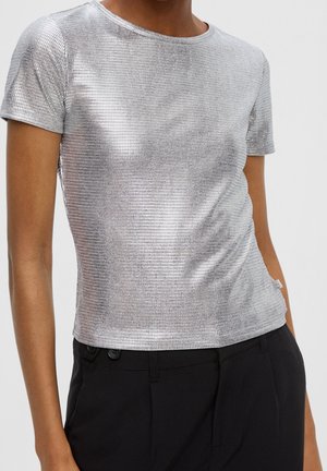 Hopeanvärinen metallinhohtoinen lyhythihainen paita ruutupintaisella tekstuurilla, pyöreällä pääntiellä ja istuvalla siluetilla, yhdistettynä mustiin housuihin.