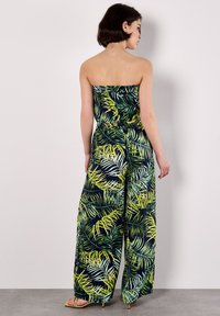 Mono sin mangas en azul marino con estampado de hojas tropicales en verde y amarillo, piernas anchas, cintura elástica y tejido ligero.