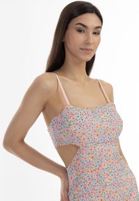 Rochie florală cu bretele roz, având un corset ajustat și laterale decupate. Flori mici multicolore pe un fundal deschis.