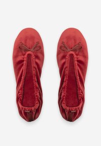 Ballerines en velours rouge avec un bout rond, des bords élastiques et de petits nœuds décoratifs à l'avant. Texture douce avec une finition lisse.