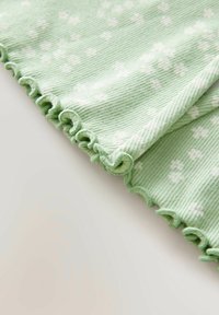 Groene textuurstof met witte bloemenpatronen en gerafelde randen, met subtiele horizontale strepen.