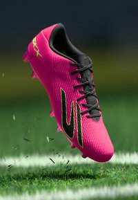 Bright pink soccer boot with black laces and accents. Feature textured surface and prominent logo. Designed for performance on grass surfaces.