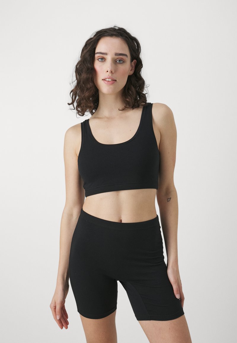 Fekete crop top és testhez simuló rövidnadrág rugalmas anyagból. Kerek nyakkivágással és varrás nélküli kialakítással a kényelem érdekében. Simaság jellemzi.