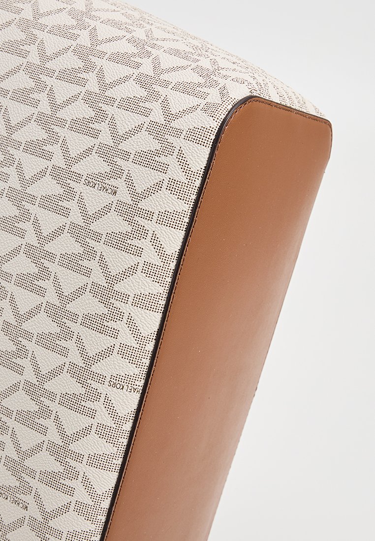 Fauteuil beige et crème avec un motif géométrique texturé sur le tissu et des bords en cuir lisse. Forme compacte et rectangulaire.