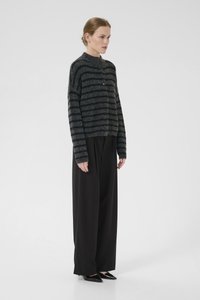 Gray striped sweater with a rounded collar and button closure, paired with loose black trousers and pointed black shoes.