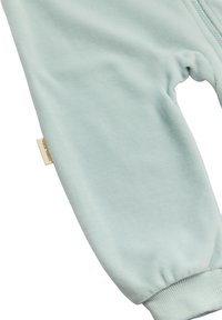 Tejido de algodón azul claro con una textura suave, que presenta puños elásticos y una pequeña etiqueta con el nombre de la marca.