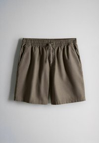 Shorts marron à taille élastique avec cordon de serrage et poches latérales, posés à plat sur un fond gris clair.